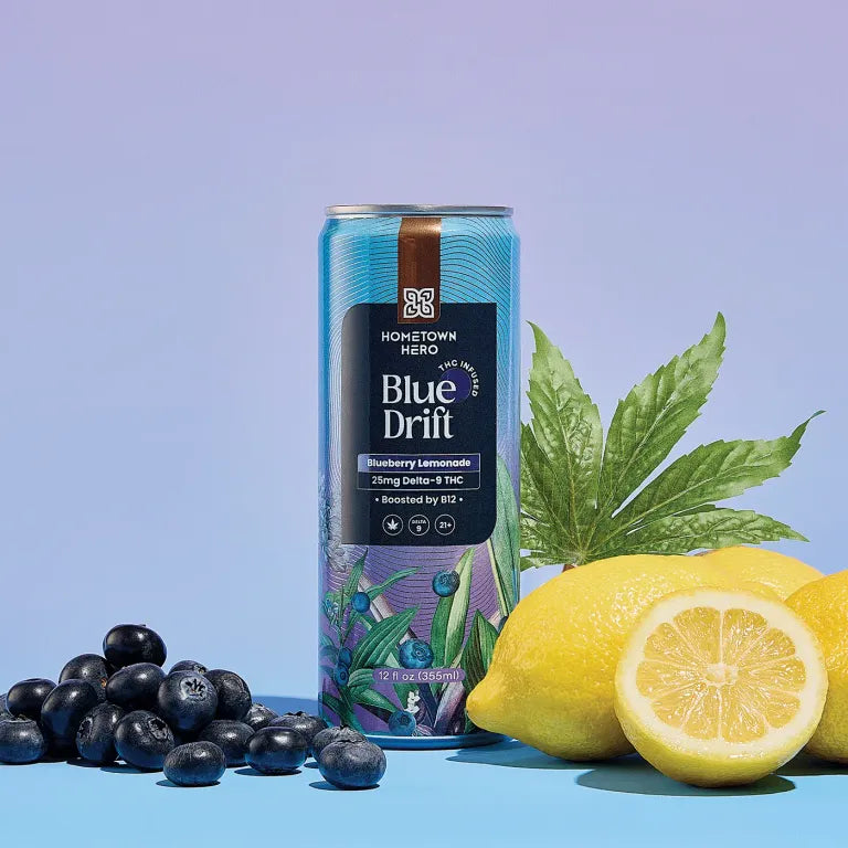 Can of Hometown Hero's Blue Drift Blueberry Lemonade 25mg Delta 9 THC surrounded by blueberries and lemons